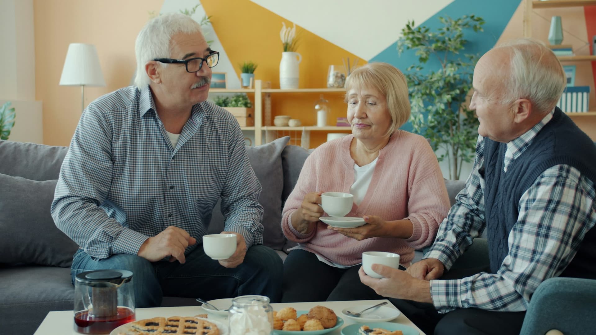 Three older friends enjoying coffee and cake together at home