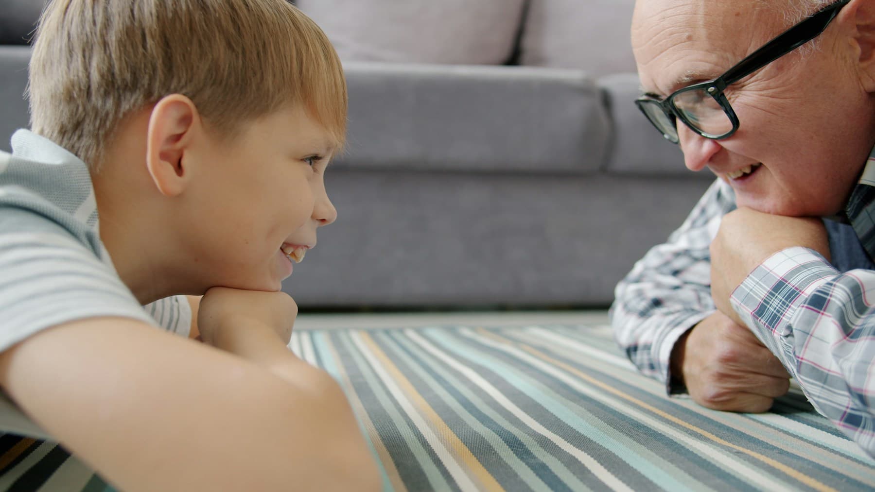 An older man and his adult grandson looking at each other and smiling