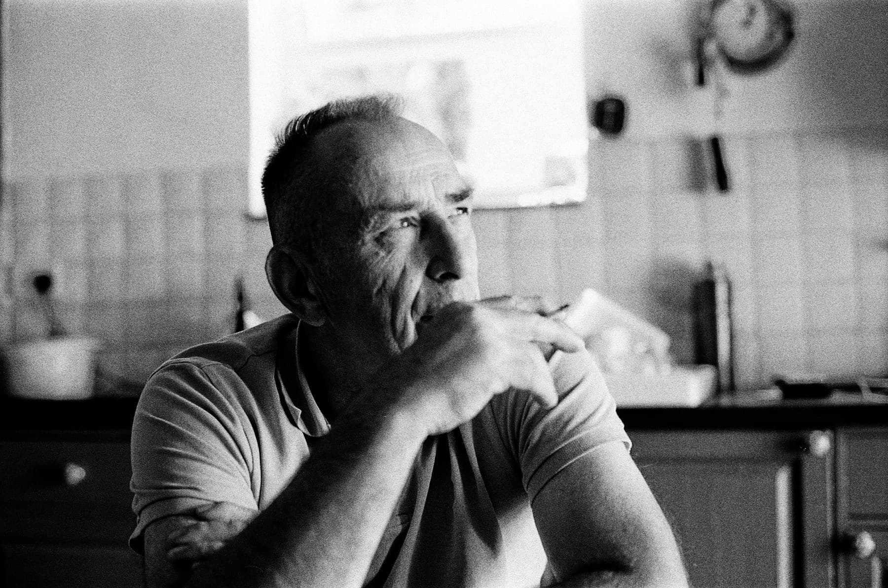An older man sitting alone at a kitchen table
