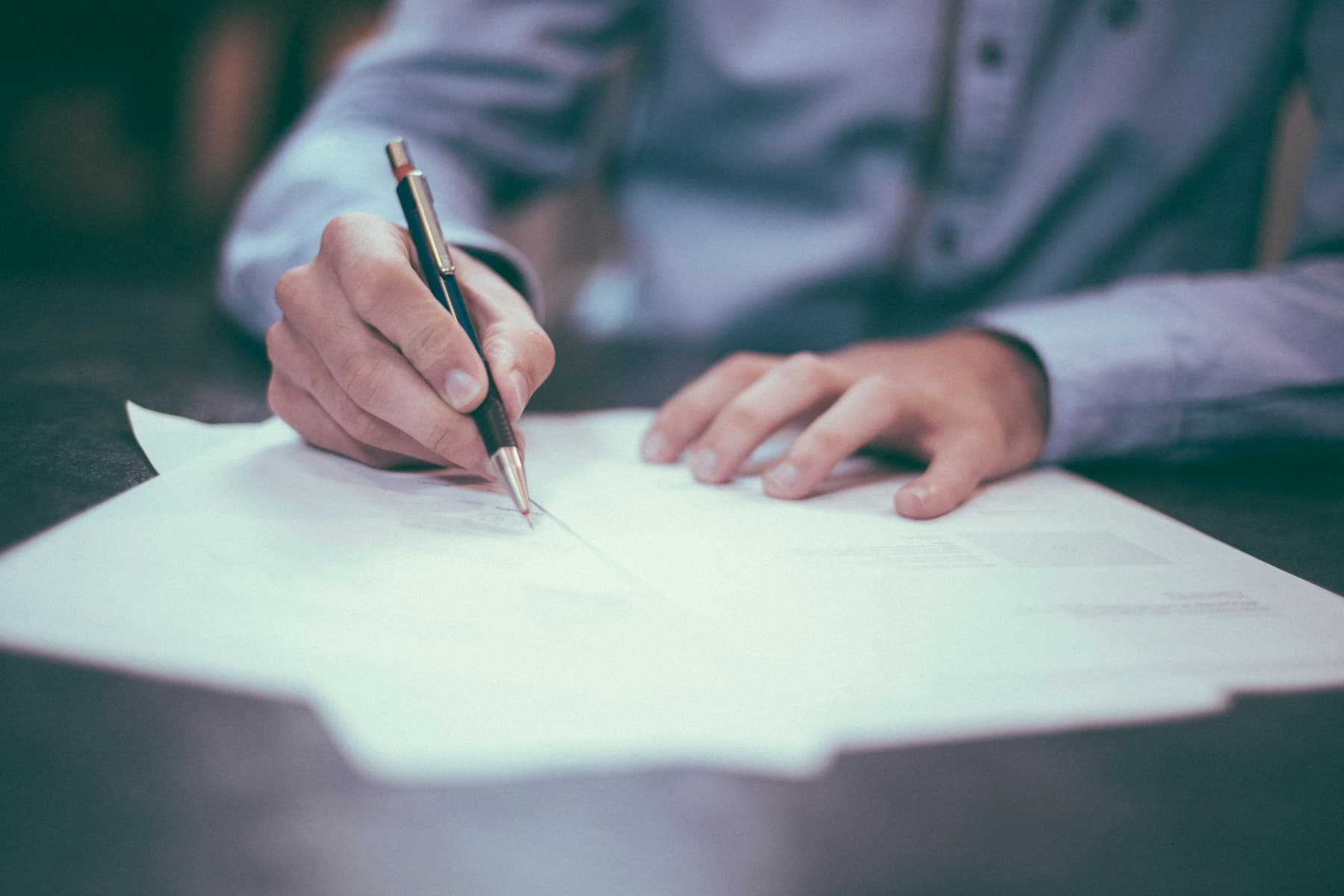 A person writing answers on a form with a pen